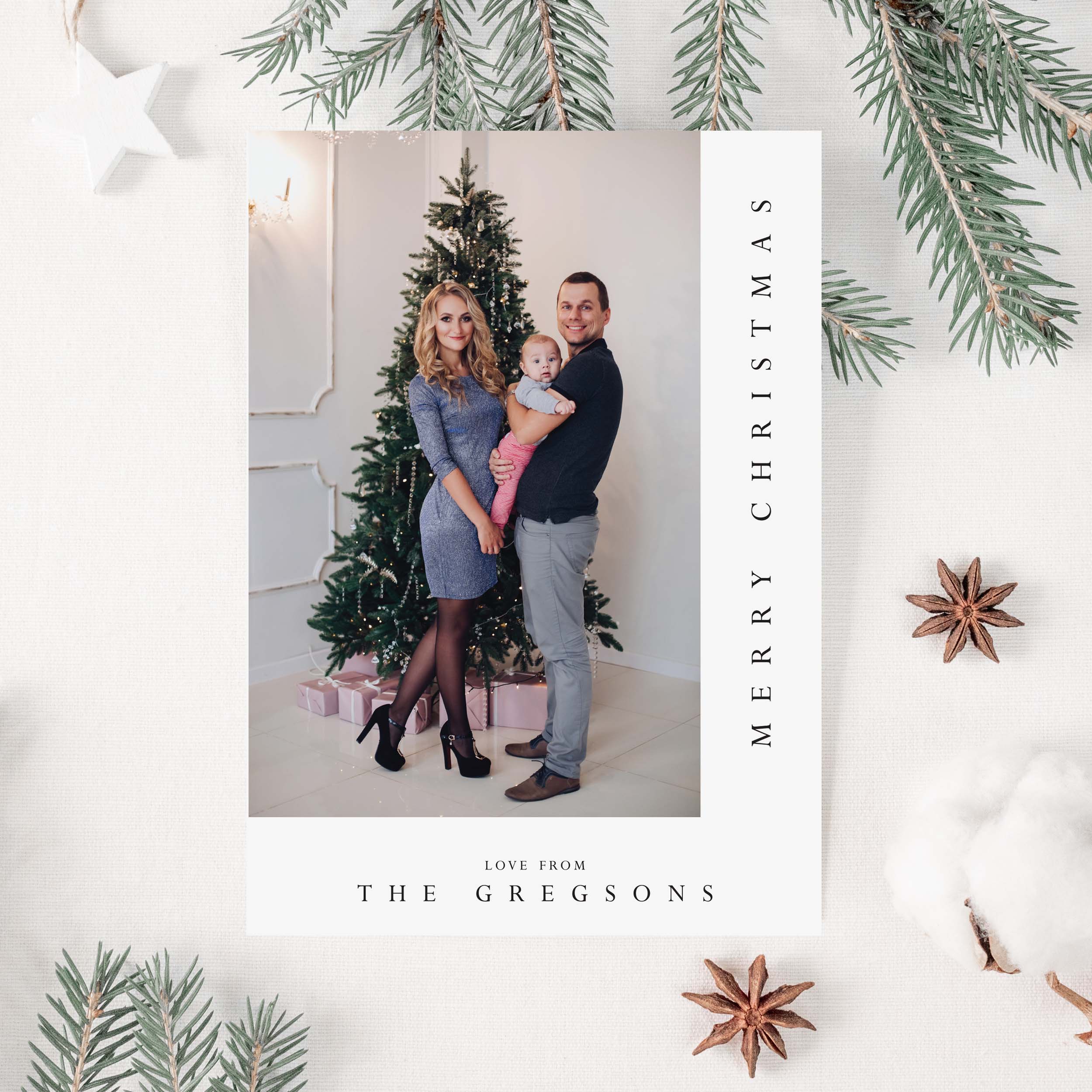 Family photo with Christmas tree and 'Merry Christmas' text on a decorative card.