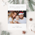 Christmas card with a family photo and festive text on a white background with Christmas decorations.