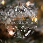 Decorative ornament with 'Our First Christmas as Mr & Mrs Taylor' text against a blurred Christmas tree background.