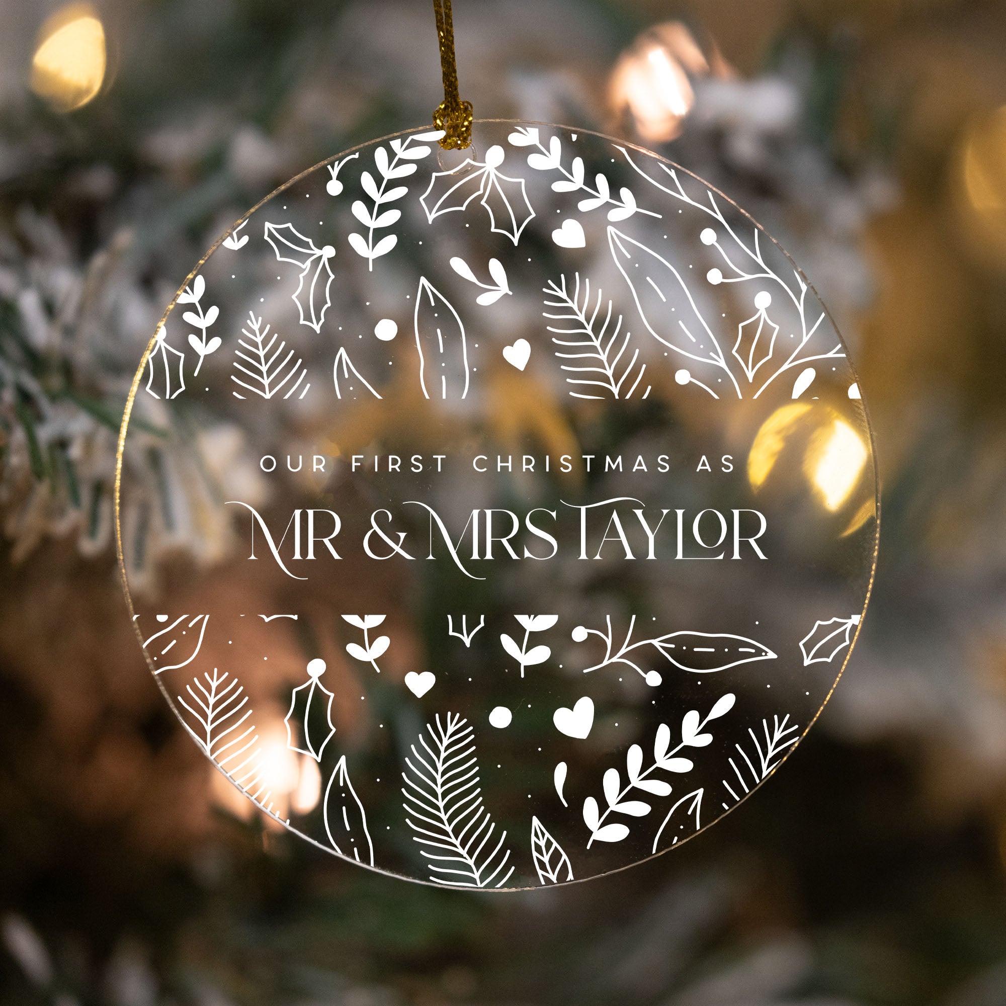 Decorative ornament with 'Our First Christmas as Mr & Mrs Taylor' text against a blurred Christmas tree background.