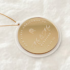 A personalized round Christmas ornament with a gold center and white outer rim, hanging from a thin gold string. The ornament is engraved with 'OUR FIRST CHRISTMAS AS Mr & Mrs HARRISON' and the date '10.