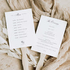 Two white wedding program cards with elegant black script and serif text, displayed on wooden sticks over a neutral beige fabric and dried floral arrangement.