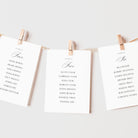 Three printed table seating cards clipped to a string with wooden clothespins against a clean white background.