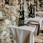 Decorated table with floral arrangements and a chair number sign in a formal setting.