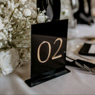 Table number '02' on a black stand with decorative elements in the background