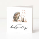 Greeting card with hedgehogs and text 'Sending you hedge-hugs' on a white background