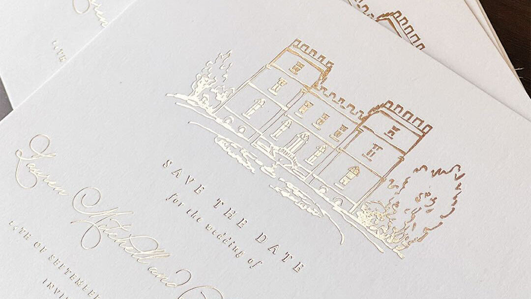White card with gold foil text and building illustration on a wooden surface