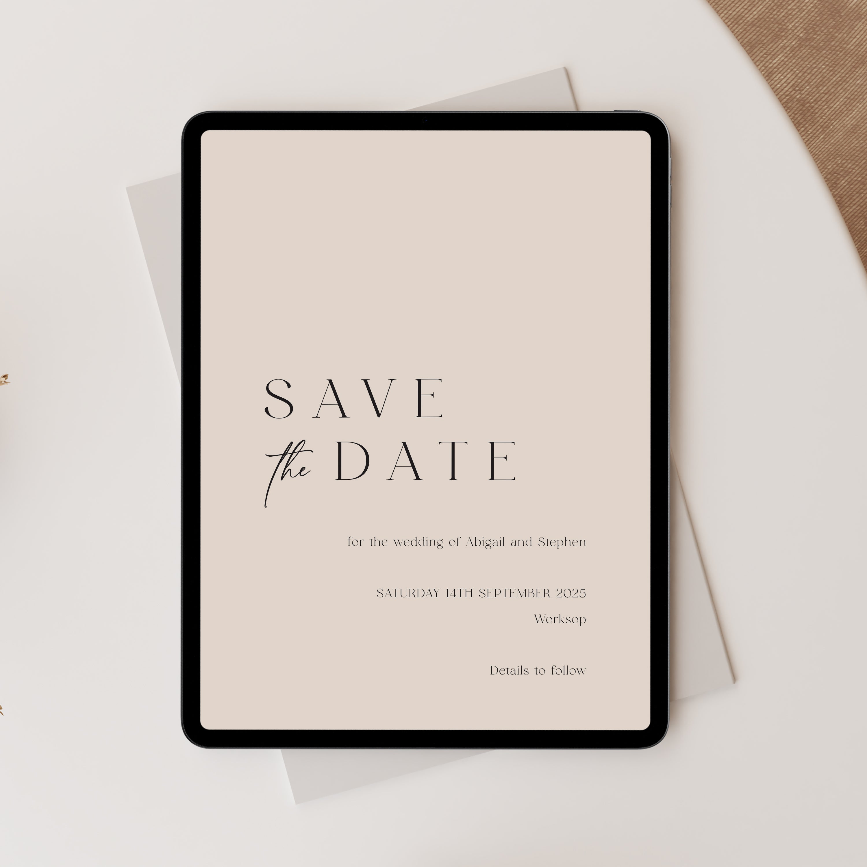Digital tablet displaying a 'Save the Date' wedding invitation on a light surface.