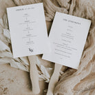 monogramed wedding programme paddle fan with wooden handle on a neutral background