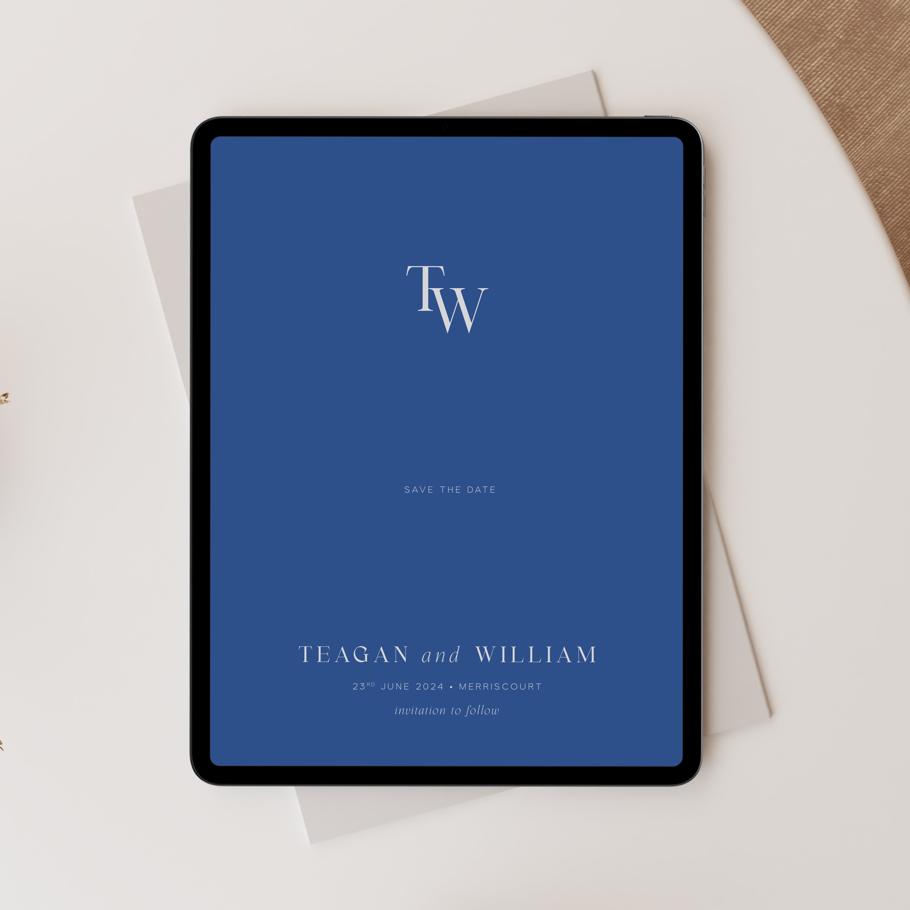 Blue save the date card on a tablet screen with 'TW' initials.