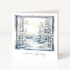 A white greeting card standing upright, printed with an open window view of a snowy winter landscape and the words 'Season's Greetings' in black script at the bottom.