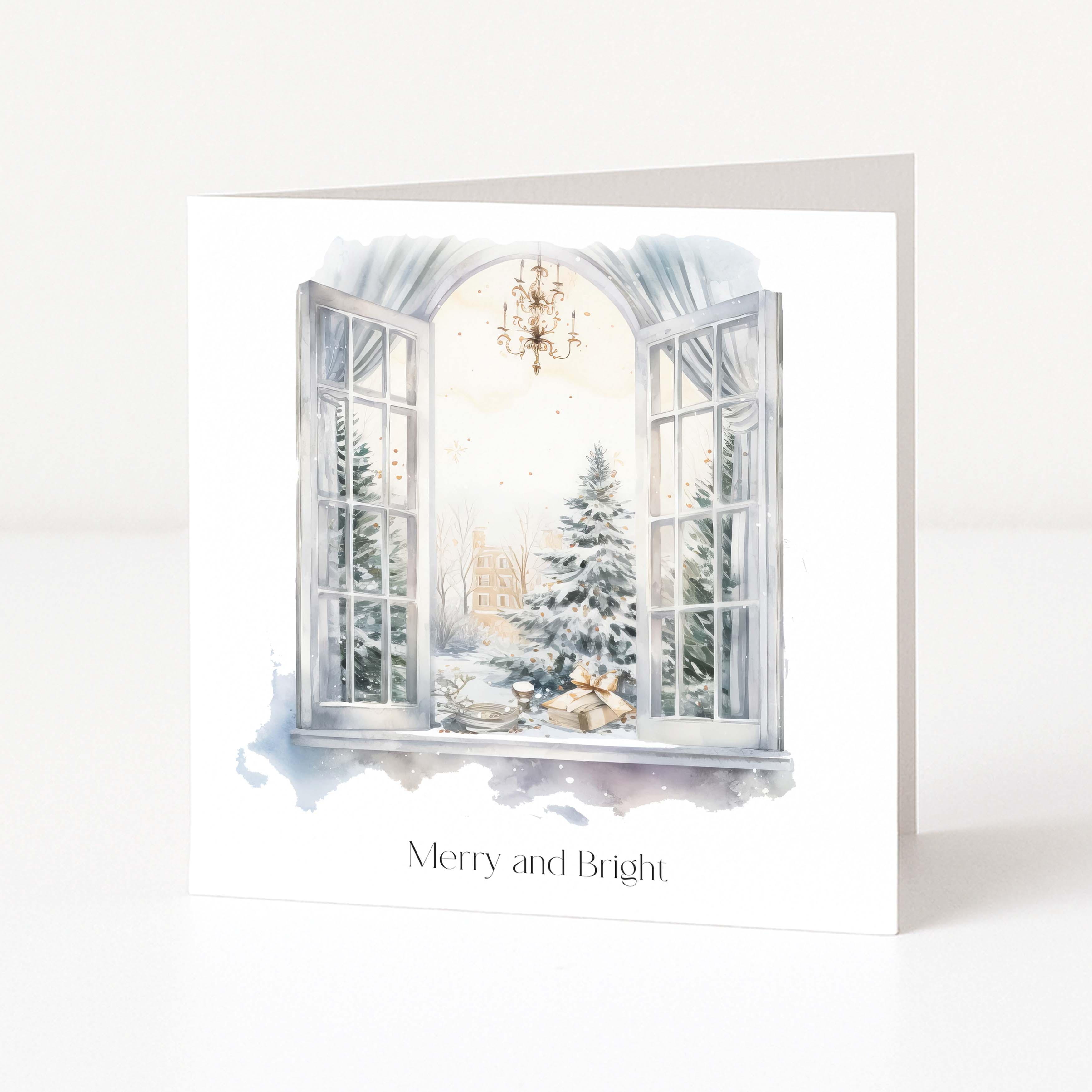 A white greeting card standing upright on a white surface, featuring an illustrated winter scene seen through an open window with snowy trees, wrapped gifts, and the text 'Merry and Bright' below.