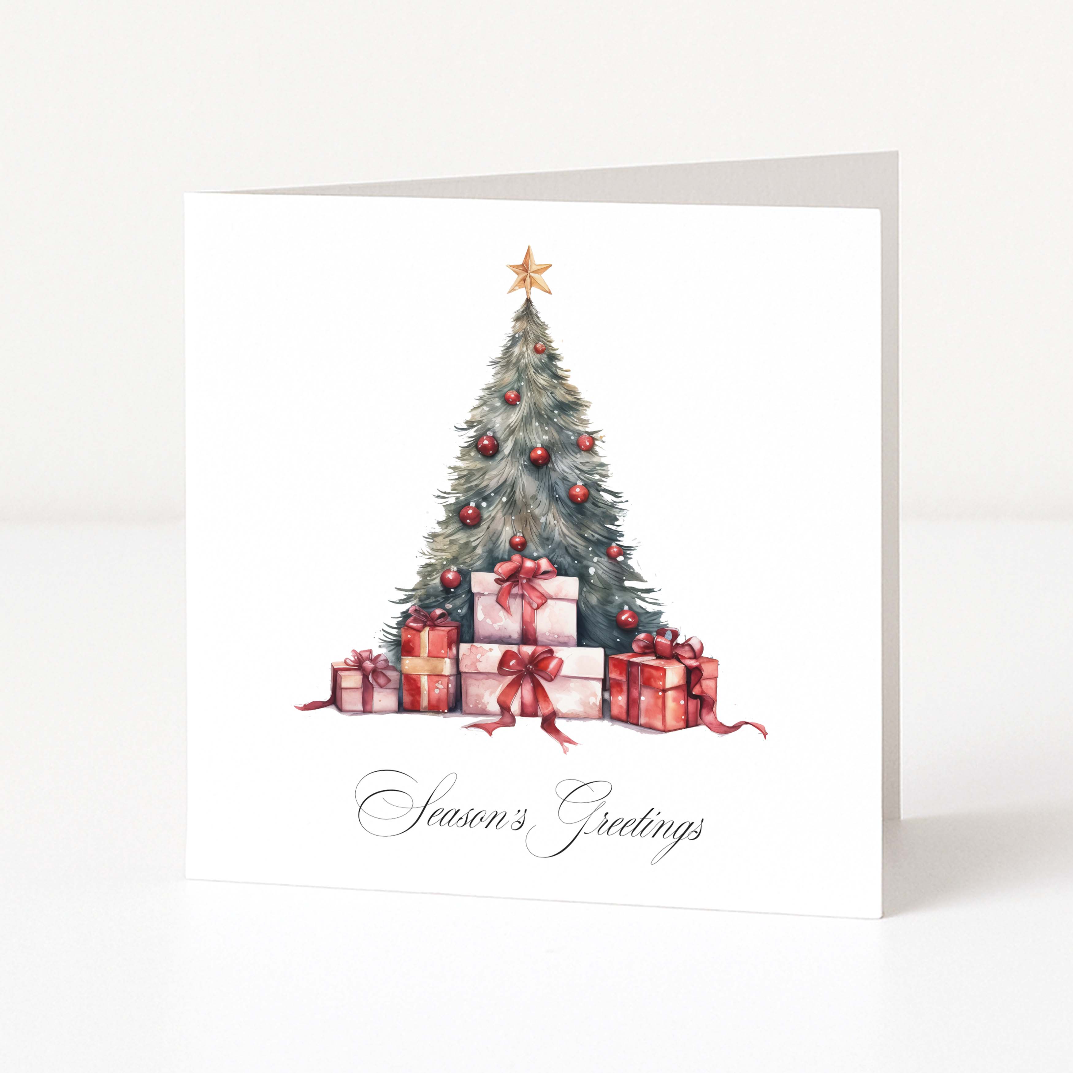 A square white Christmas greeting card standing upright on a white surface, featuring a watercolour-style Christmas tree with red ornaments, wrapped presents, and the script text 'Season's Greetings' at the bottom.