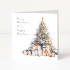 A square white Christmas greeting card with a watercolour-style Christmas tree, gold ornaments, wrapped presents, and the text 'Merry Christmas and a Happy New Year,' shown standing against a clean white background.