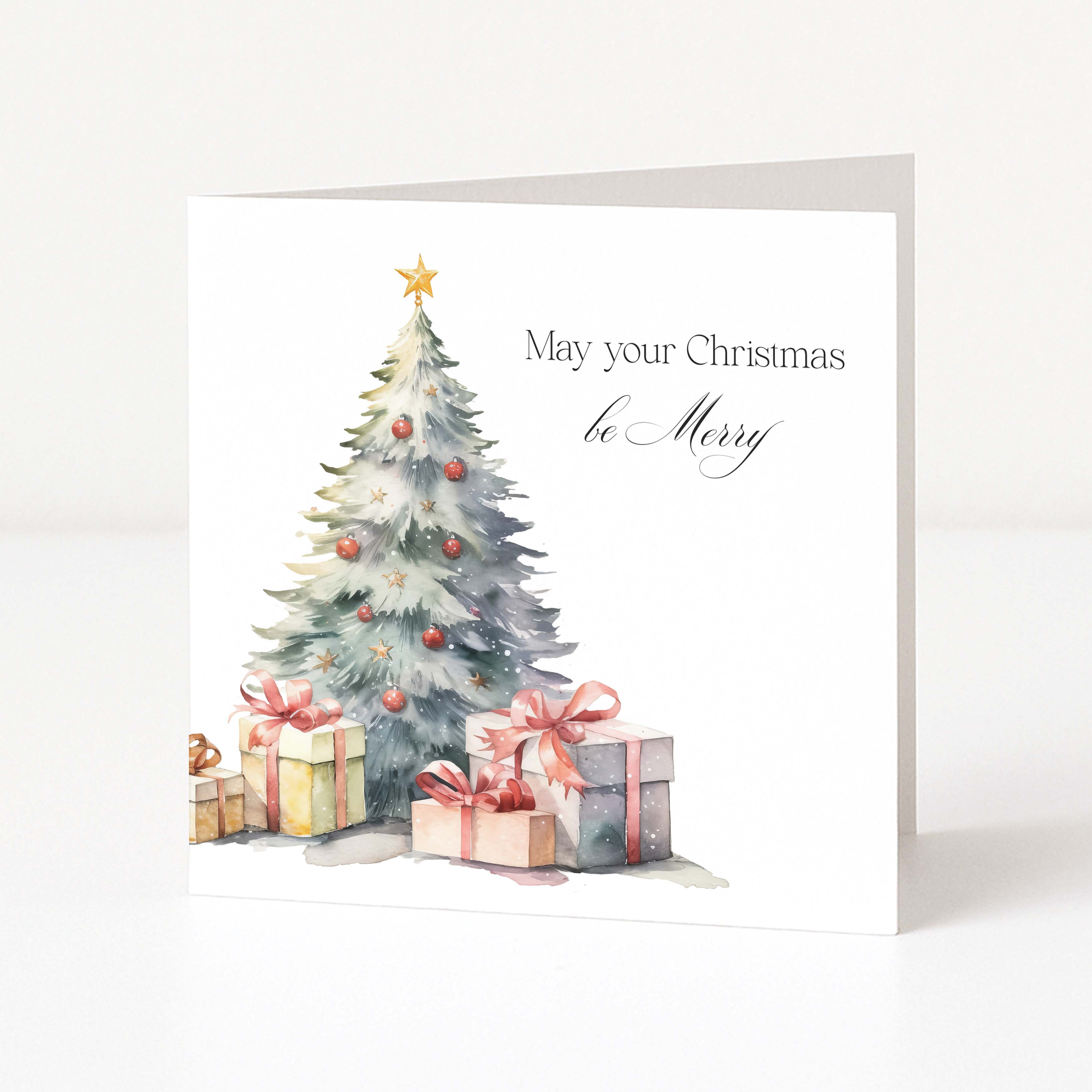 A white Christmas greeting card standing upright, featuring a watercolor illustration of a decorated tree with wrapped presents and the text 'May your Christmas be Merry'.