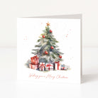 A square white Christmas greeting card standing upright, printed with a watercolor Christmas tree, red ornaments, wrapped presents, and the phrase 'Wishing you a Merry Christmas' in red script.