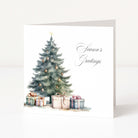 A square white Christmas greeting card standing upright, printed with a watercolour Christmas tree, ornaments, wrapped presents, and the words 'Season's Greetings' in black script.