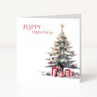 A square Christmas greeting card standing upright on a white surface. The card has a white background with the words 'HAPPY CHRISTMAS' in red script at the upper left and a watercolor-style decorated Christmas tree with red ornaments and wrapped gifts at the lower right.