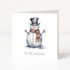 A white Christmas greeting card featuring a watercolour illustration of a snowman wearing a dark top hat and a brown scarf, with the text "tis the season" printed below.