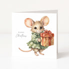 A square white Christmas greeting card featuring a watercolour illustration of a small mouse in a green dress holding a wrapped gift box, with the text 'Happy Christmas' on the left.