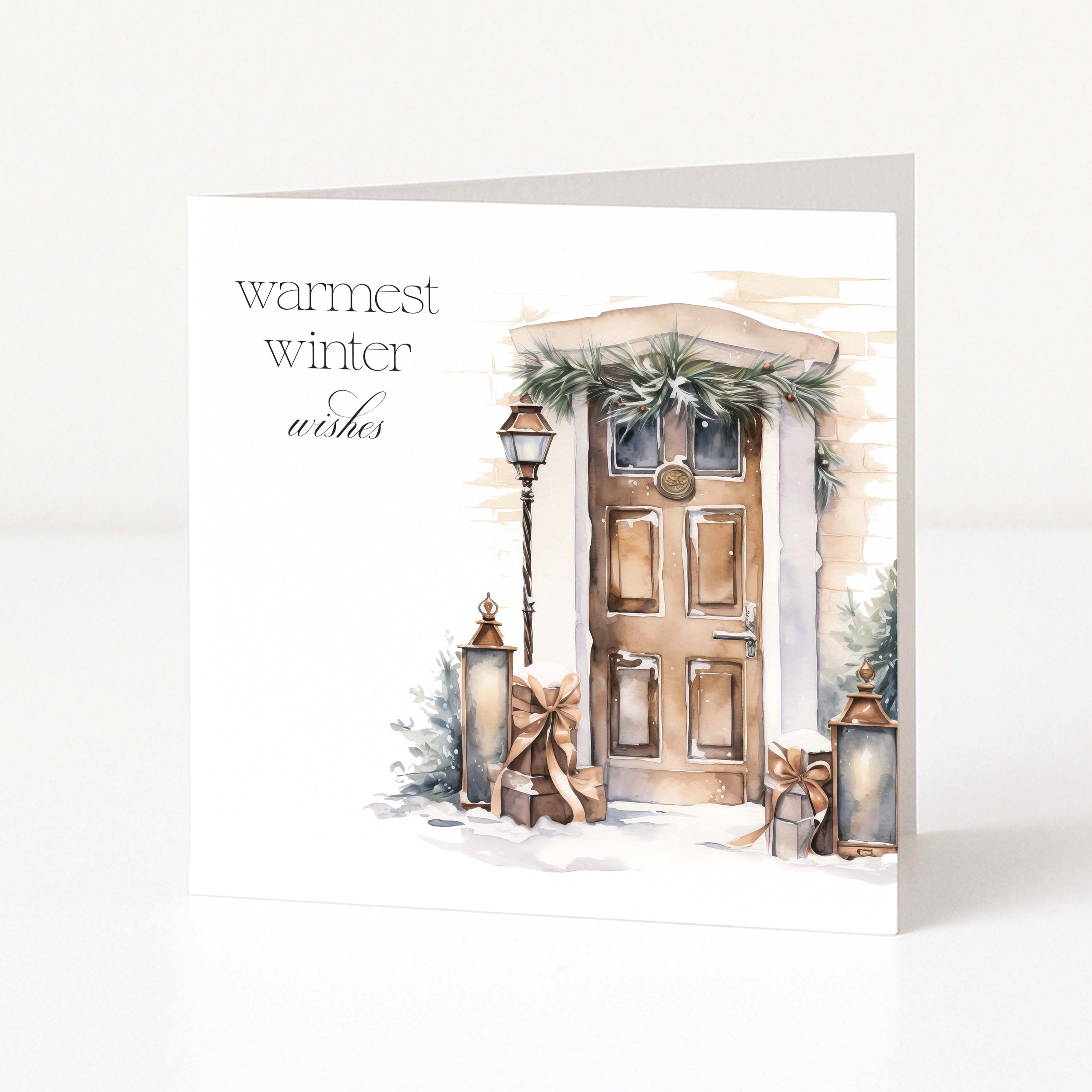 A square greeting card with a watercolor-style illustration of a holiday door, wreath, lantern, and wrapped gifts, with the text 'warmest winter wishes' on a white background.