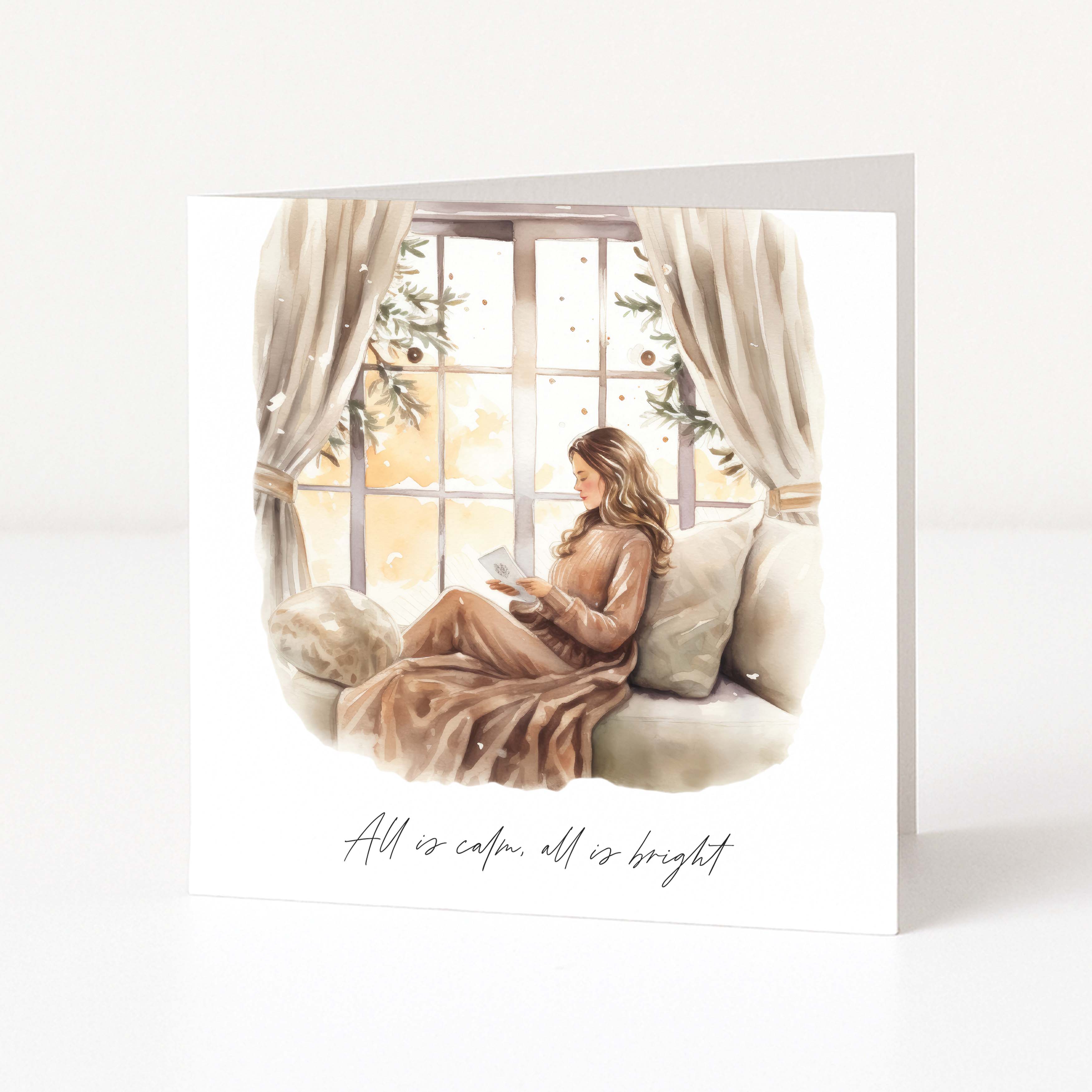 A square Christmas card with a watercolour illustration of a woman reading on a sofa by a window, with the text 'All is calm, all is bright' printed below, shown on a clean white background.