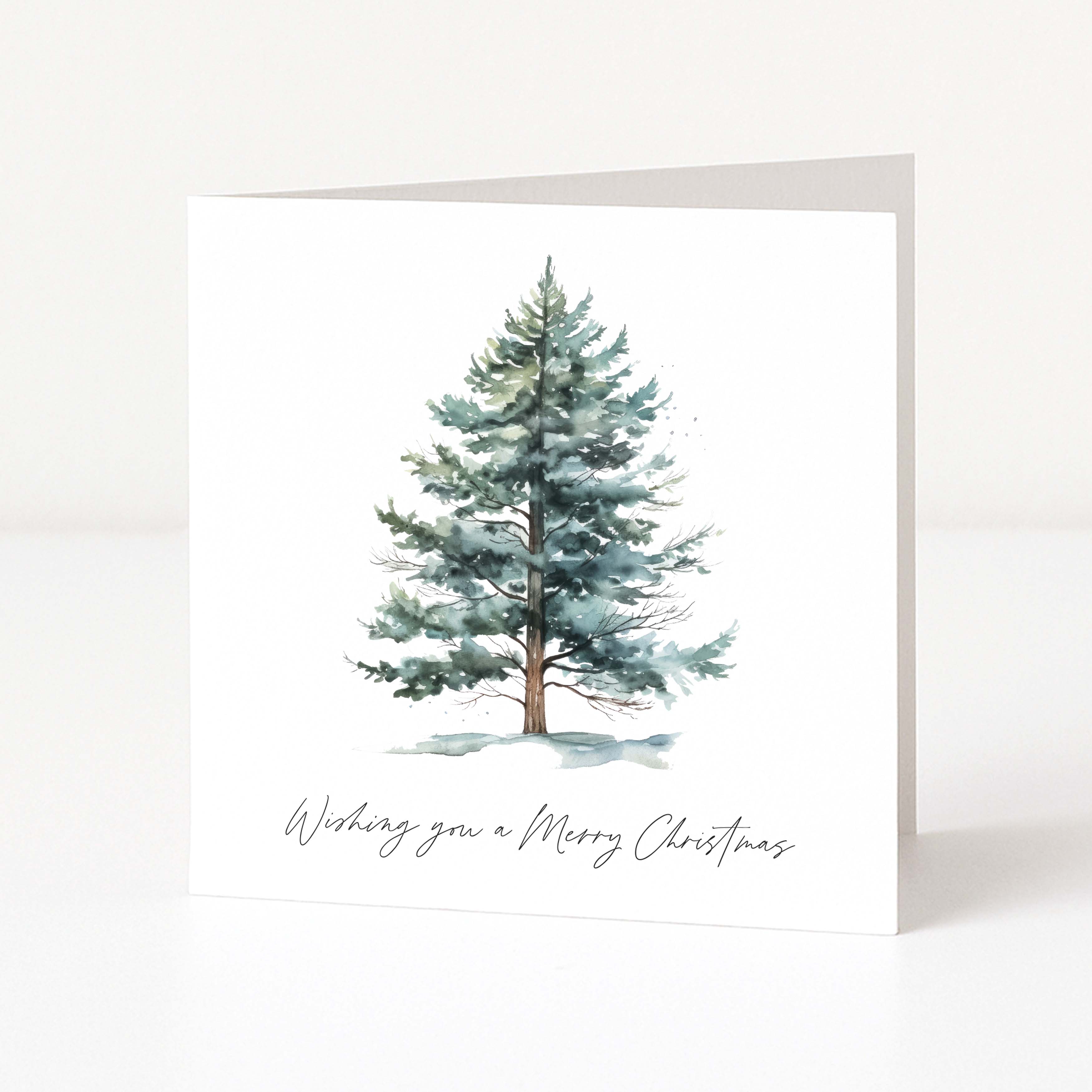 A square white Christmas greeting card with a watercolour illustration of a snow-dusted evergreen tree and the handwritten text 'Wishing you a Merry Christmas' at the bottom, shown standing against a clean white background.