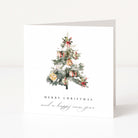 A white Christmas greeting card standing upright, featuring a watercolour illustration of a decorated tree with ornaments and the text 'MERRY CHRISTMAS and a happy new year' below.