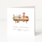 A white Christmas greeting card standing upright, featuring a watercolor illustration of holiday decorations on a shelf above the text 'MERRY CHRISTMAS and a happy new year'.