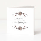 A white greeting card standing upright, featuring delicate floral illustrations in muted grey and taupe with the text 'Wishing you a Merry Christmas and a happy new year' in black script and serif type.