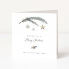 A white Christmas greeting card standing upright on a light surface, printed with a Christmas branch, hanging ornaments, a snowflake, a star, and the text 'Wishing you a Merry Christmas and a Happy New Year'.