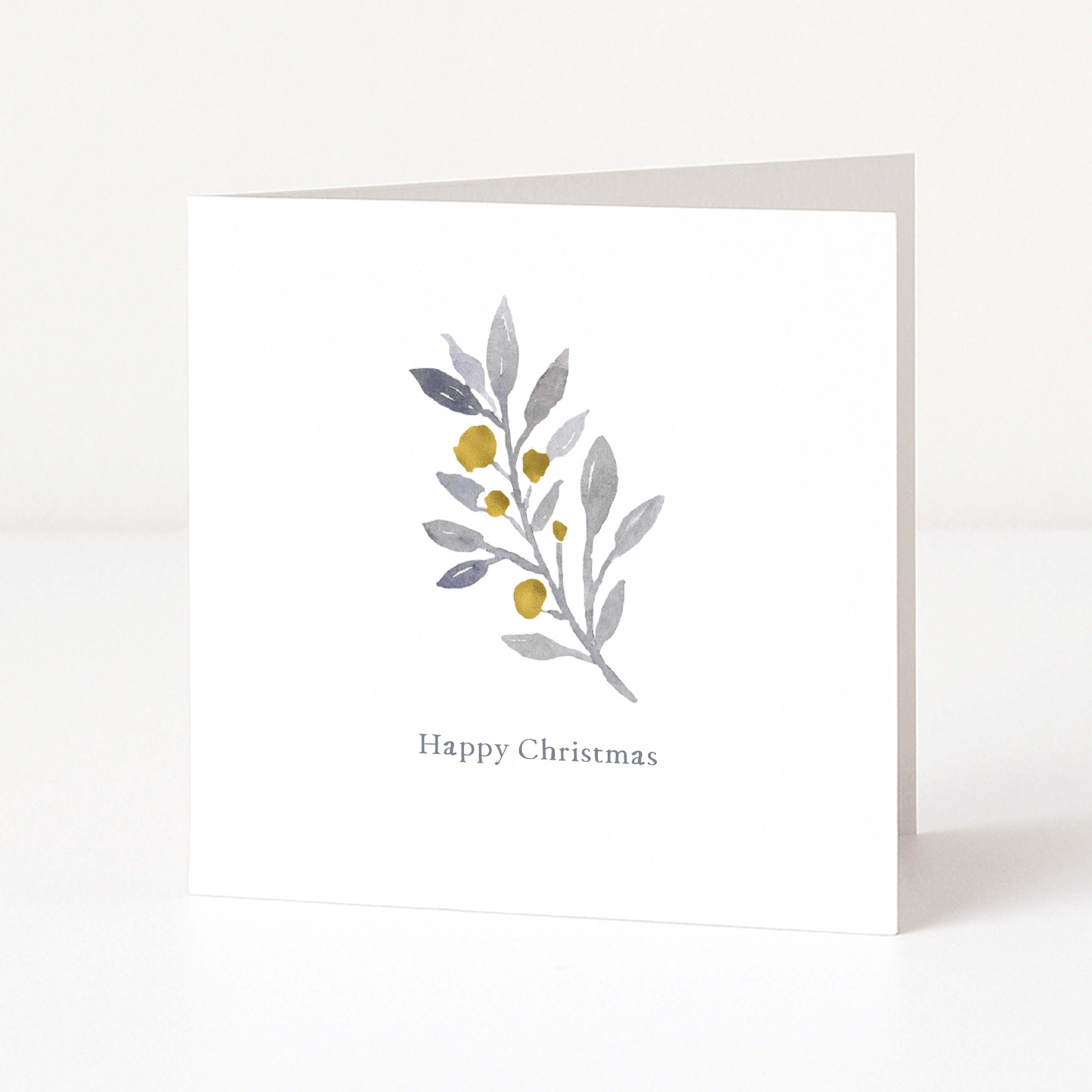 A white square Christmas greeting card standing upright on a white surface, featuring a watercolour-style botanical branch with muted grey-green leaves and small gold berries above the words 'Happy Christmas' in a delicate gray font.