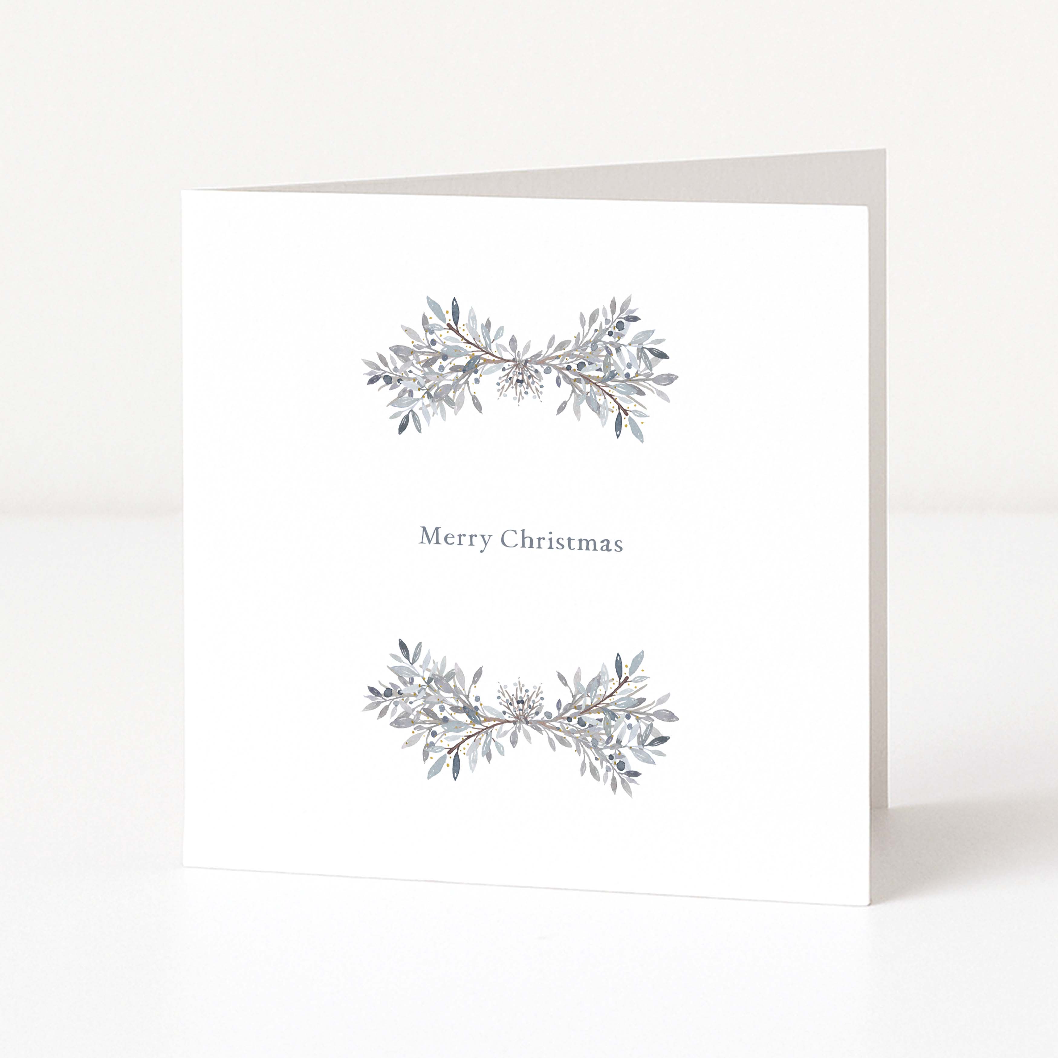 A white square Christmas greeting card standing upright on a white surface, with two delicate grey and silver leafy garlands and the words 'Merry Christmas' centered on the front.