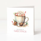 A white Christmas greeting card standing upright, featuring an illustrated hot chocolate mug topped with marshmallows, candy canes, and greenery, with the text 'SEASON'S GREETINGS' below.