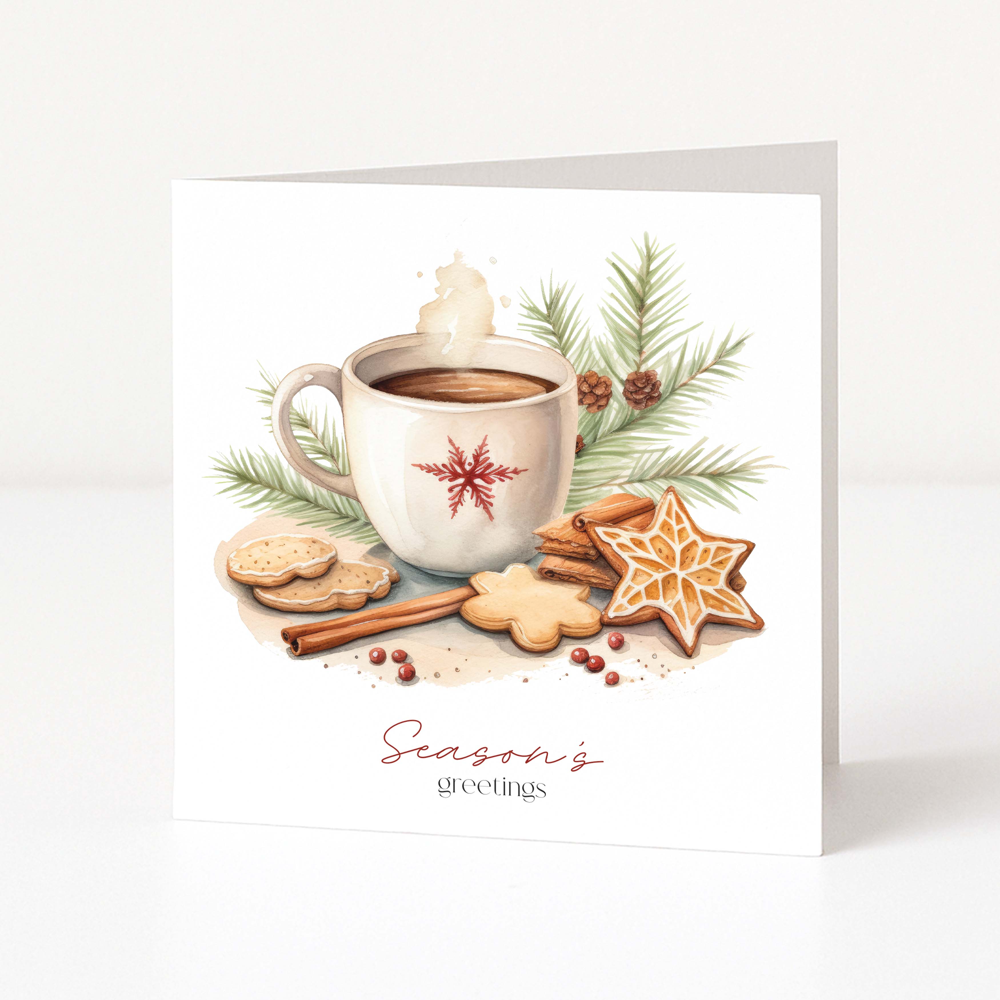 A square white Christmas greeting card standing upright, printed with a warm holiday illustration of a mug of hot cocoa, cookies, cinnamon sticks, pine branches, and the text 'Season's greetings' in red script and serif type.