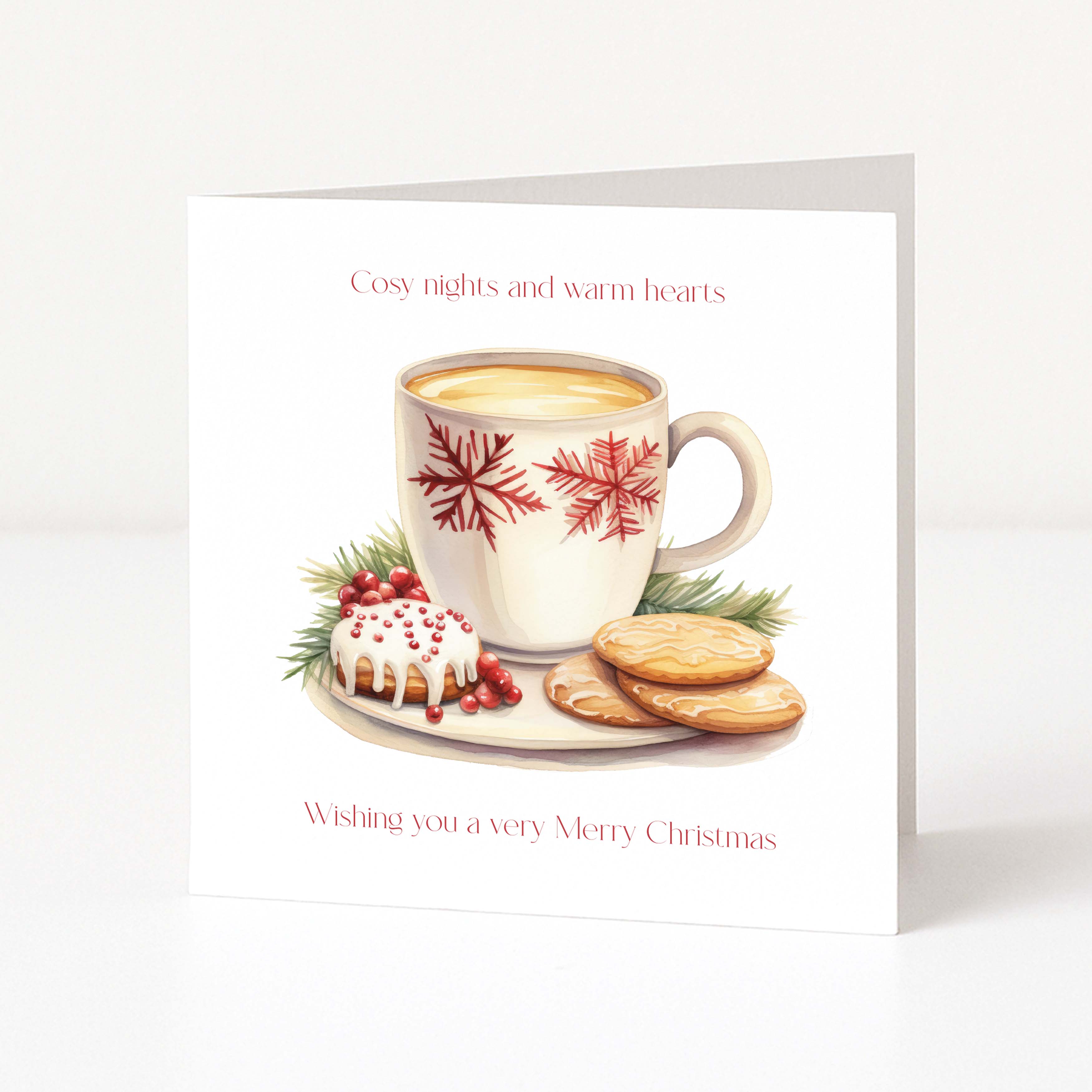 A square white Christmas greeting card standing upright, printed with the phrase 'Cosy nights and warm hearts' at the top and 'Wishing you a very Merry Christmas' at the bottom. The center shows an illustrated white mug with red snowflake patterns, filled with a warm drink, alongside a small decorated pastry, cookies, and greenery on a plate.