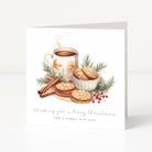 A square white Christmas greeting card standing upright on a light surface. The front features an illustrated holiday still life with a mug of hot drink, cookies, cinnamon sticks, greenery, and red berries, plus the text 'Wishing you a Merry Christmas and a happy new year'.
