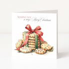 A square Christmas greeting card standing upright on a white surface. The card features an illustration of stacked cookies tied with a red ribbon, with the text 'WISHING YOU a very Merry Christmas' printed at the top.