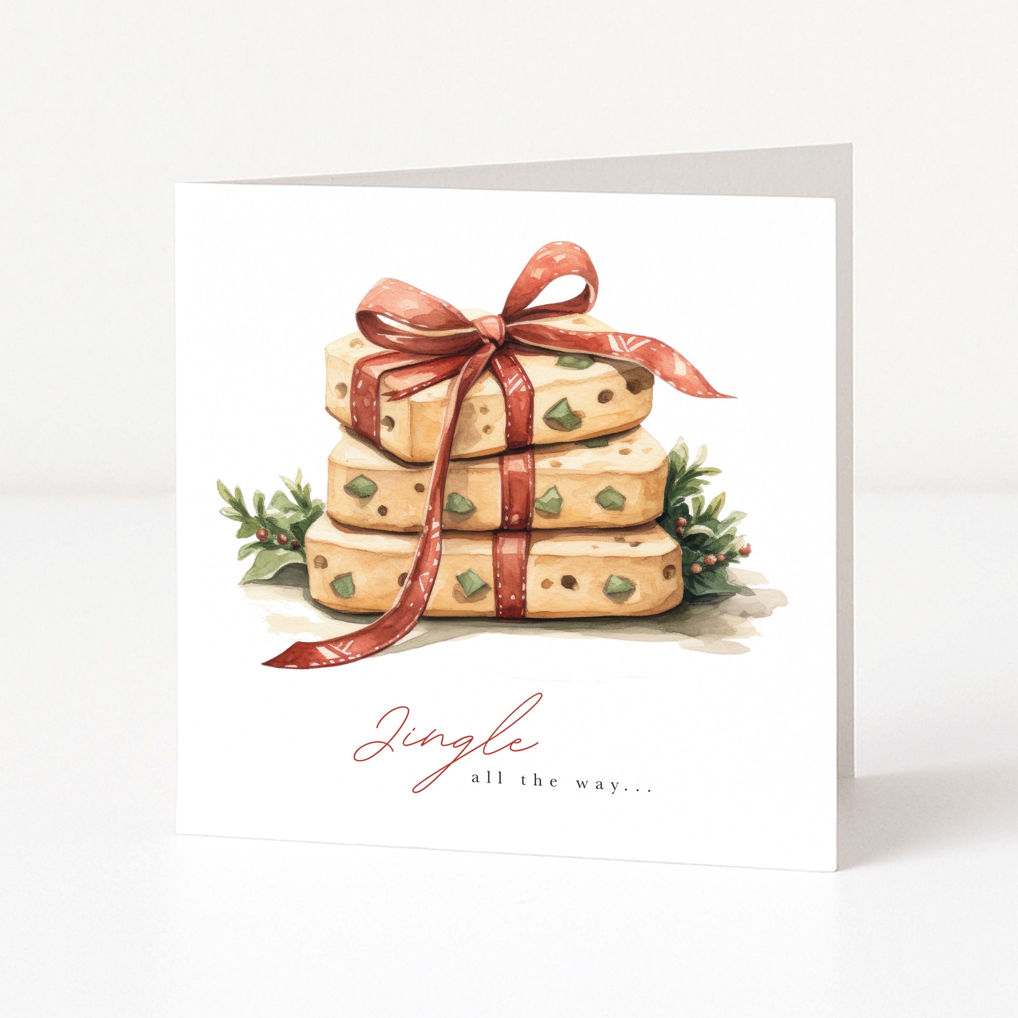 A white Christmas greeting card featuring an illustration of three stacked Christmas cookies tied with a red ribbon, with small green holly leaves and the text 'Jingle all the way.