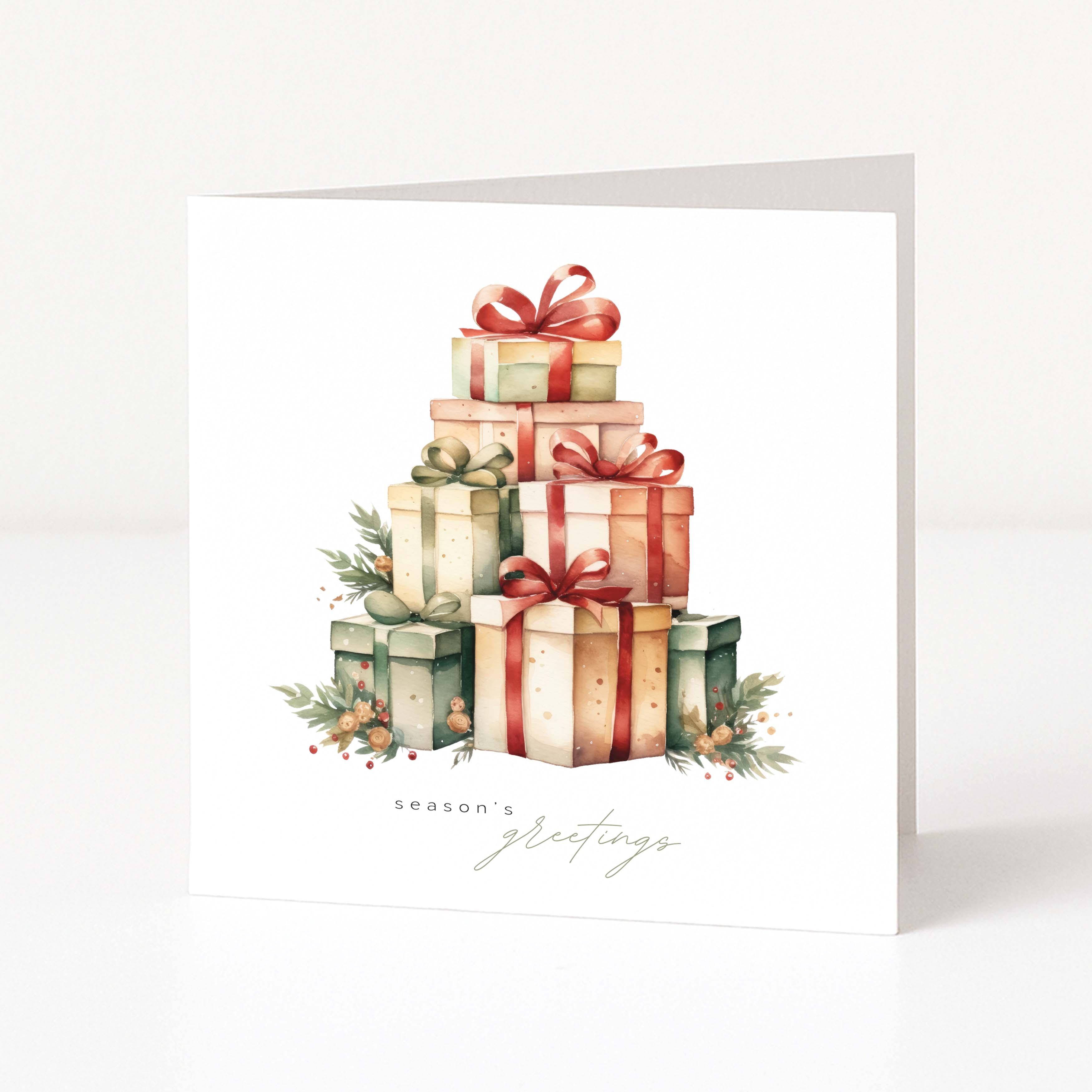 A white square Christmas greeting card standing upright, featuring a watercolour illustration of stacked gift boxes wrapped in red, green, and beige paper with bows, plus small evergreen sprigs and berries. The card reads 'season's greetings' in a delicate script at the bottom.