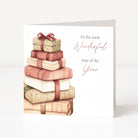 A white Christmas greeting card standing upright, featuring an illustration of stacked wrapped presents in soft beige, pink, and cream tones with a red ribbon. The right side of the card reads, 'It's the most Wonderful time of the Year' in black and dusty rose script.