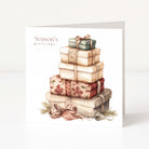 A square Christmas greeting card standing upright on a white surface, featuring an illustration of stacked gift boxes with bows and the text 'Season's greetings' on the front.