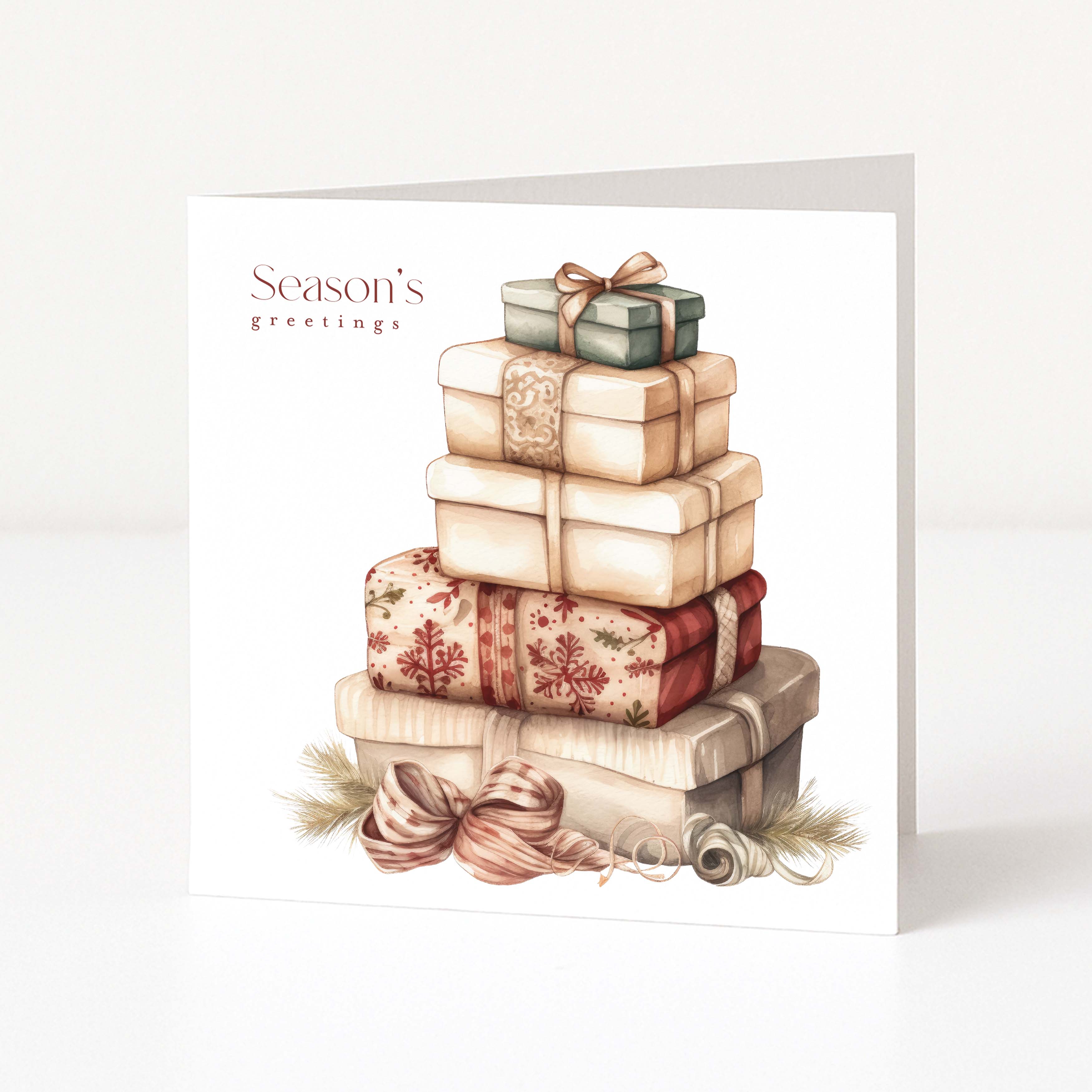 A square Christmas greeting card standing upright on a white surface, featuring an illustration of stacked gift boxes with bows and the text 'Season's greetings' on the front.
