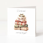 A white Christmas greeting card standing upright on a light grey surface, featuring an illustration of wrapped gifts stacked on top with the text 'Peek the boxes.