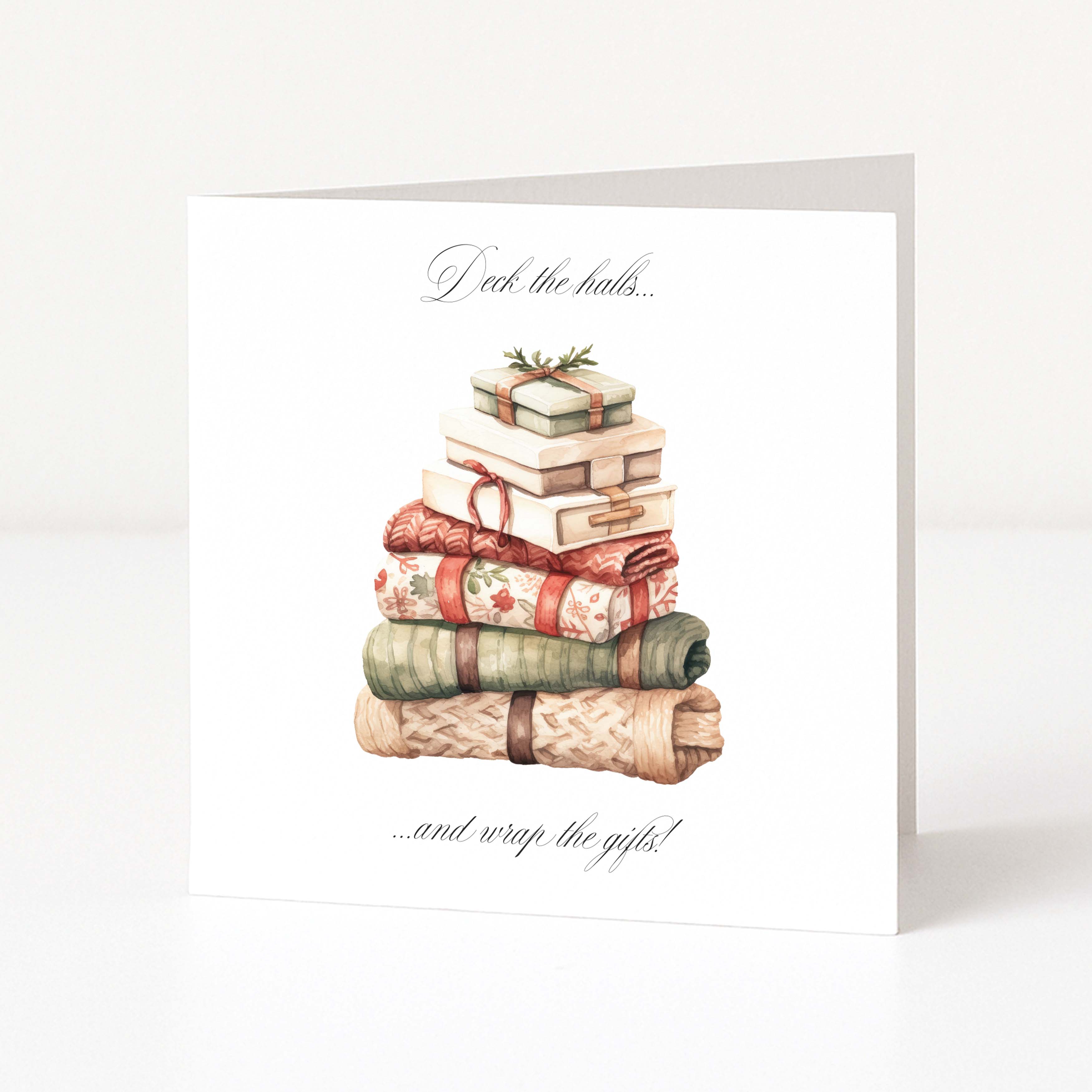 A white Christmas greeting card standing upright on a light grey surface, featuring an illustration of wrapped gifts stacked on top with the text 'Peek the boxes.