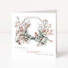 A white greeting card standing upright on a white surface, featuring a watercolour-style winter wreath with red berries, snowy greenery, a small red cardinal, and the text 'IT'S THE MOST Wonderful TIME OF THE YEAR'.