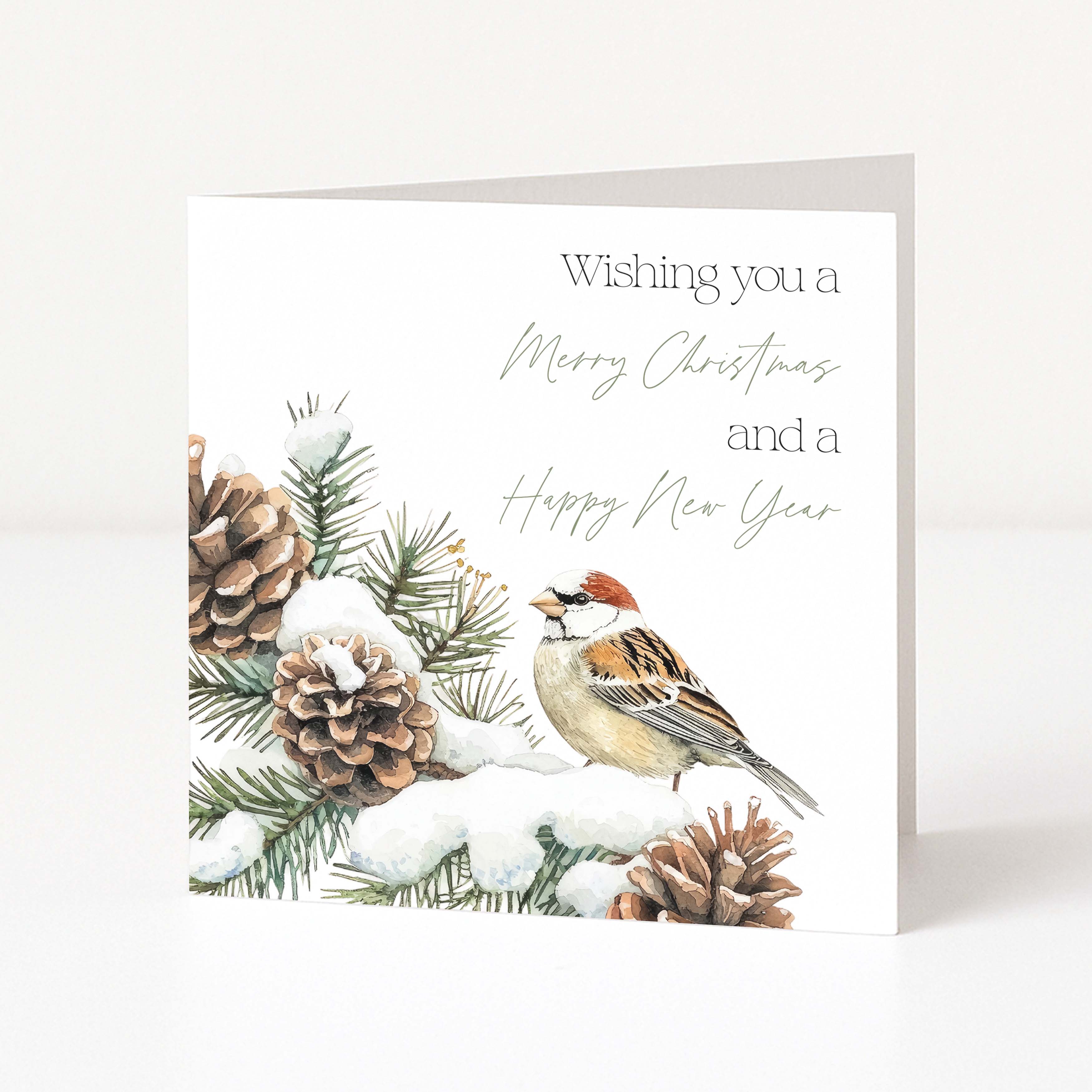 A square white greeting card standing upright on a light grey surface. The card features an illustration of a small house sparrow perched among snowy pine branches and pinecones, with the text 'Wishing you a Merry Christmas and a Happy New Year' in dark grey and pale sage lettering.