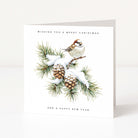A square white Christmas greeting card standing upright on a light neutral surface. The front features an illustration of a small brown-and-white bird perched on a snow-dusted pine branch with pinecones, with the text 'WISHING YOU A MERRY CHRISTMAS' at the top and 'AND A HAPPY NEW YEAR' at the bottom.