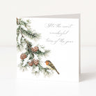 A square white greeting card standing upright, printed with a winter pine branch, pinecones, a small bird, and the phrase “It’s the most wonderful time of the year” in gray script.