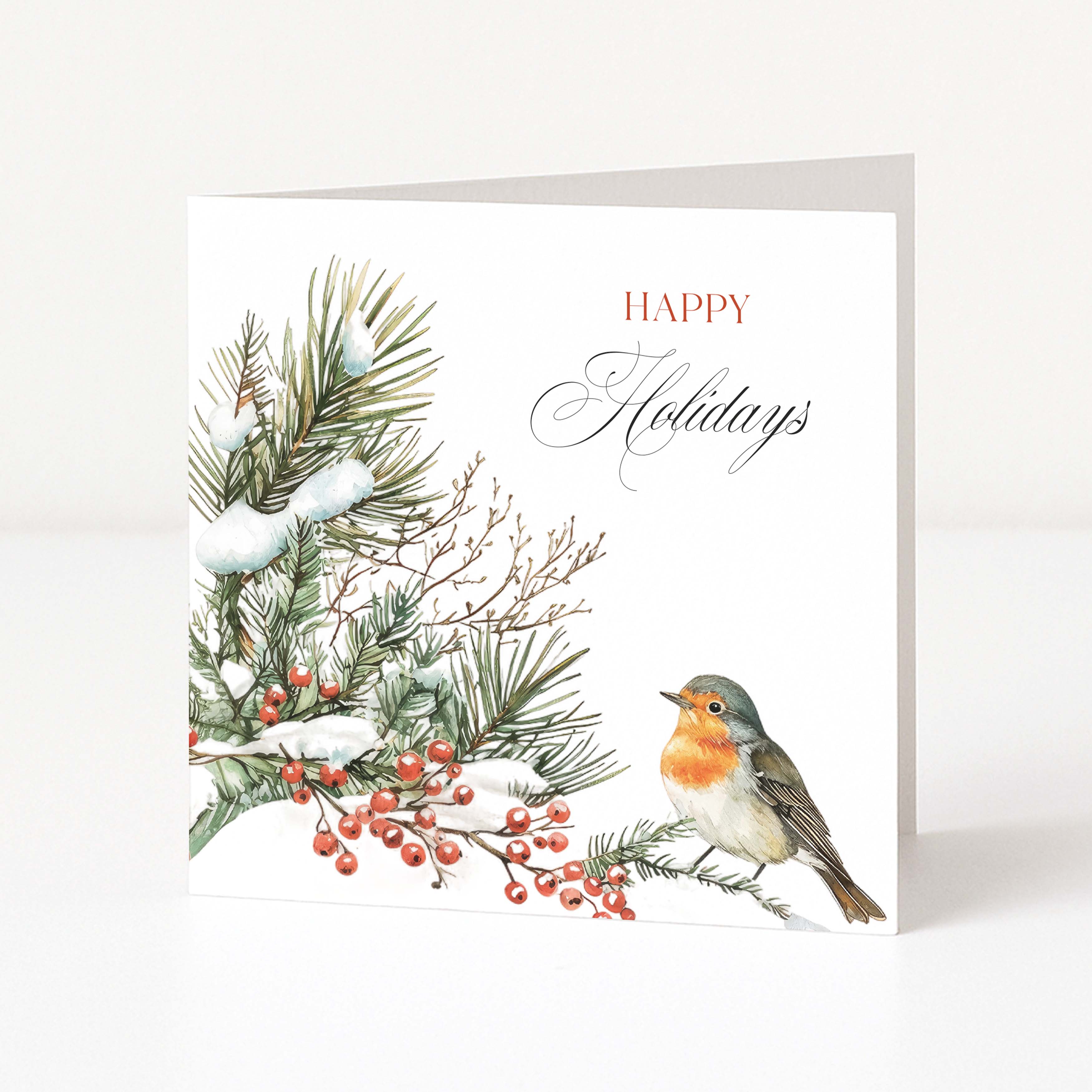 A square white holiday greeting card standing upright on a light neutral surface. The card features a watercolor-style winter illustration with snow-dusted pine branches, red berries, and a robin bird on the lower right, alongside the words “HAPPY Holidays” in red and gray script.